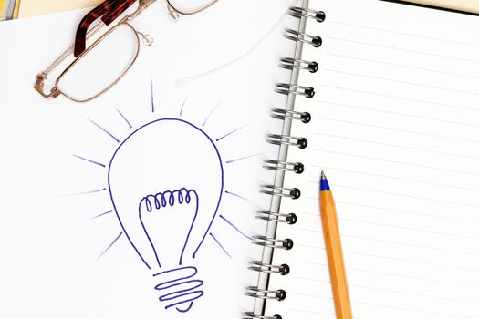 Light Bulb Background idea concept - with spiral notebook and pen.