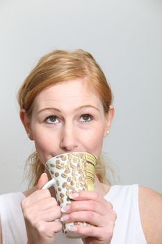 Young woman enjoys her coffee and looks up - vertically
