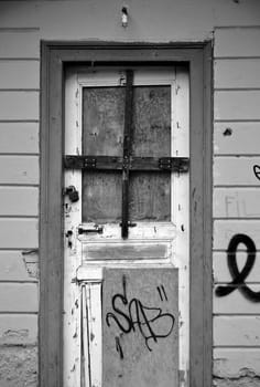 Boarded up door and weathered wall surface of an abandoned house.