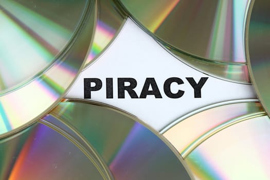 Piracy word written on a pile of dvd disc.