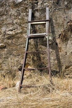 Rusty broken ladder against a weathered wall surface. Abstract background.