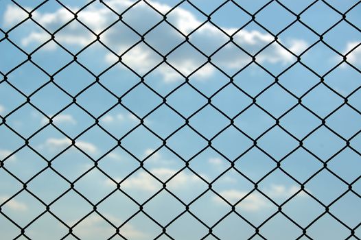 Chain link wired fence pattern against blue sky.