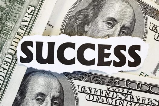 Monetary Success concept - success written over dollars.