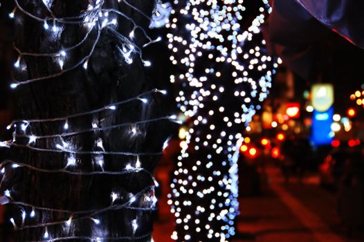 Tree trunk with Christmas lights. Urban night scene.