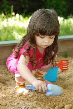 The girl playing to a sandbox. Caucasian the child, park of rest