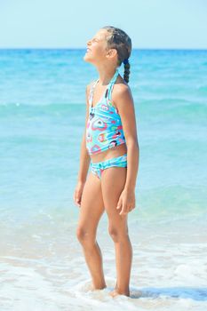 Beautiful girl standing on the beach and sunbathe