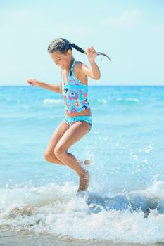 Beautiful girl jumping in the waves on the beach