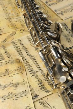Old saxophone and notes. The Musical instrument laying on notes with classical music of the beginning of 17 centuries
