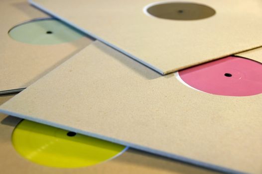 Pile of cardboard sleeve vinyl music records with colorful blank labels.
