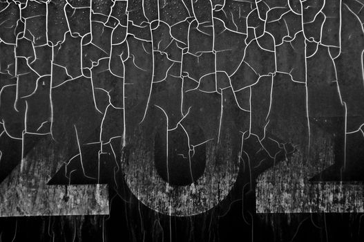 Cracked plastic surface with faded typography. Black and white.