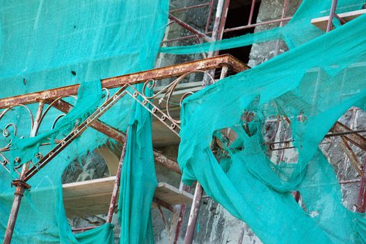 Abandoned mansion renovation. Vintage rusty metal shed and torn scaffold debris netting.