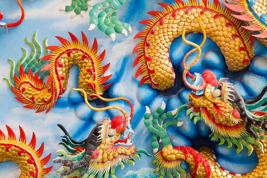 Statue of a dragon on the wall, in a Chinese temple, in the daytime.