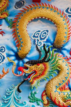 Statue of a dragon on the wall, in a Chinese temple, in the daytime.