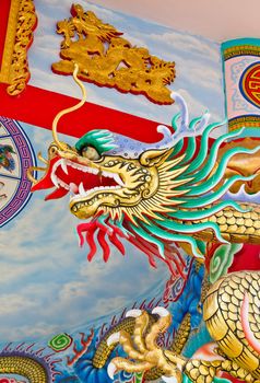 A statue of a dragon on a pole in the Chinese temple in the daytime.