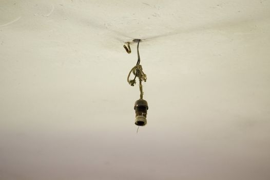 Broken light bulb electrical wiring and ceiling detail inside an abandoned house.