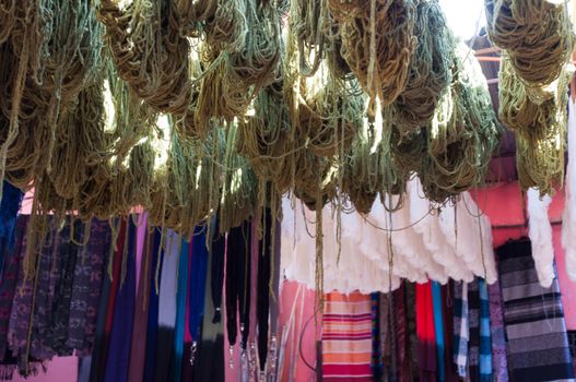 Dyed and drying wool in Medina in Marrakech, Morocco with scarves in the background