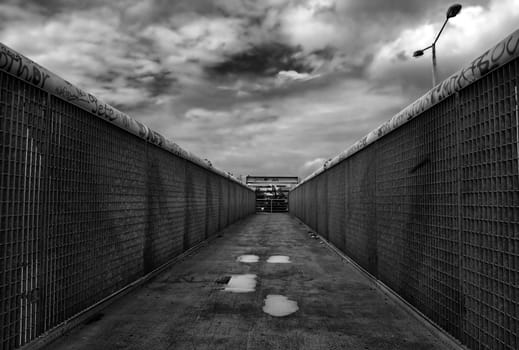 Pedestrian overpass. Metal bridge crossing above the motorway. Black and white.