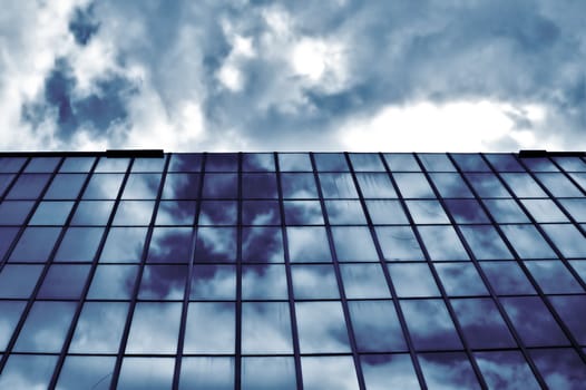Overcast sky mirrored on modern glass building. Architectural detail.