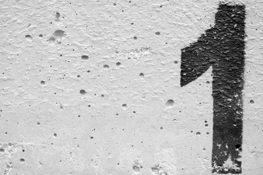 Number one stencil sprayed on rough concrete surface. Black and white.