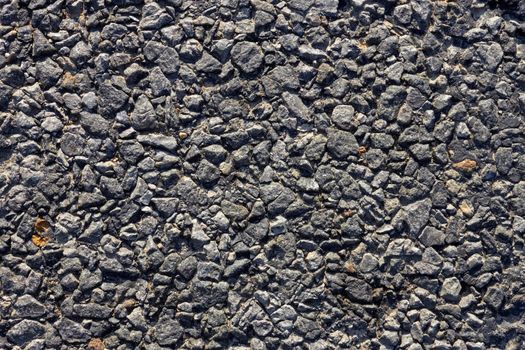 Fragment of the road surface with small stones and bitumen. Close-up 