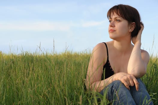 The girl on field. The young girl on green field on a background of the dark blue sky