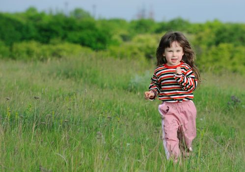 The running girl on a green floor. The happy child on a spring meadow