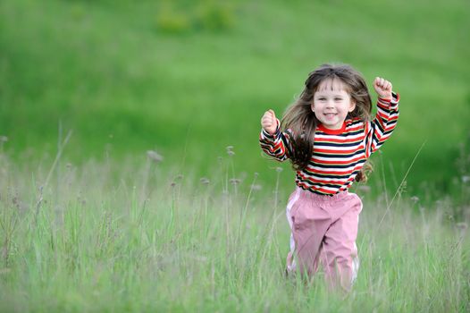 The running girl on a green floor. The happy child on a spring meadow
