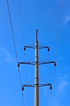 High voltage transmission pillar against a background of a blue sky, view from below