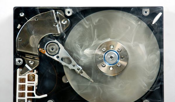 Defect hard disk drive with smoke. Open drive as symbol for data loss.