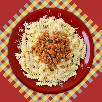 Dish of italian fusilli pasta and bolognese sauce mixed with mushrooms and carrots.