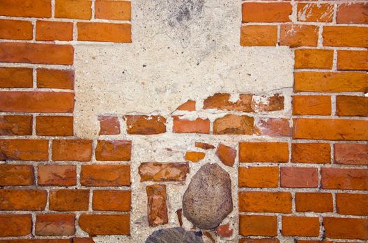 Fragment of ancient red brick wall with stones ant cement in it.