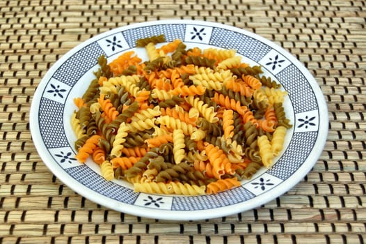 Three different flavors of raw fusilli pasta. Italian food background.