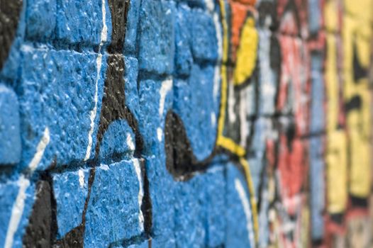 Rough stone wall surface covered with colorful graffiti. Urban street art.