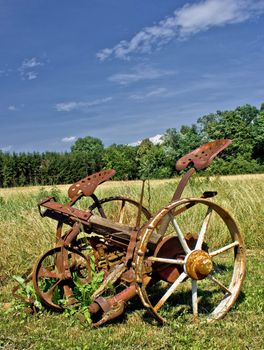 Traditional rusty horse powered grass mower on meadow in summer