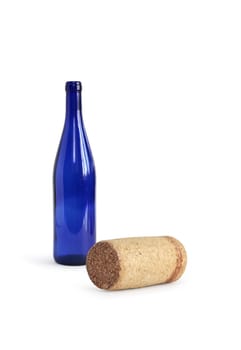 Cork lying near open empty blue bottle on white background