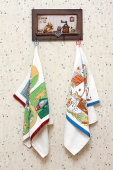 Dishtowels hung on wooden hatrack on background sulphur wallpaper