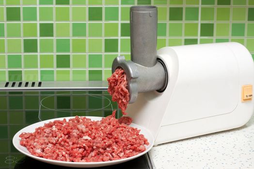 Meat grinder on kitchen, mincemeat on background of the tiled bar