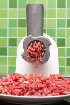 Meat grinder on kitchen, mincemeat on background of the tiled bar