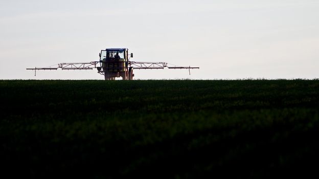 tractor spraying agricultural pesticide on field