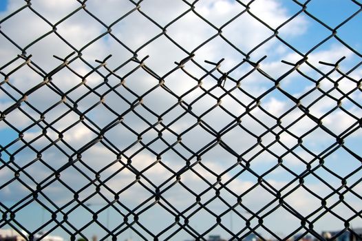 Wire mesh chain link fence pattern against blue sky.