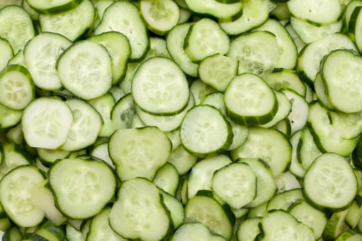 Much cut fresh cucumbers put by background