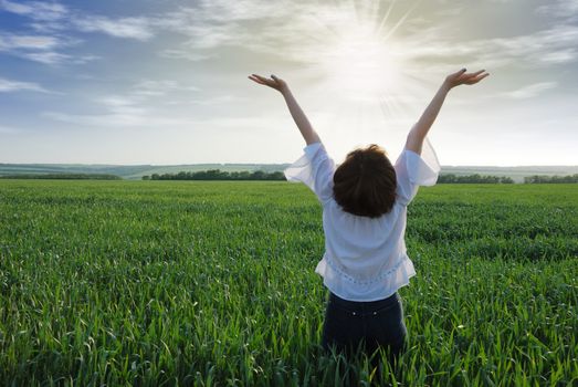 The girl on a field. The woman with the lifted hands to the sky on a green meadow