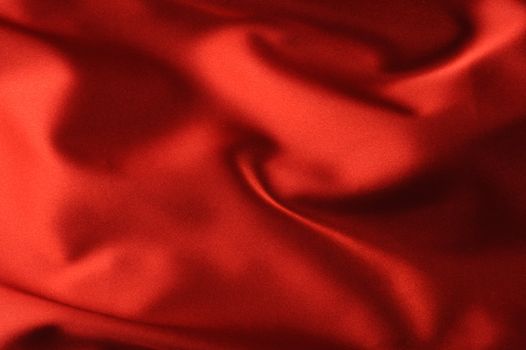 red satin background. A satiny fabric with beautiful light-shadow waves