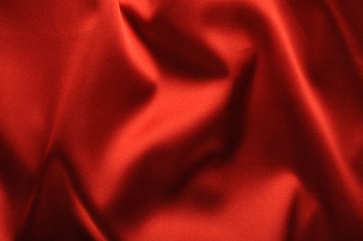 red satin background. A satiny fabric with beautiful light-shadow waves