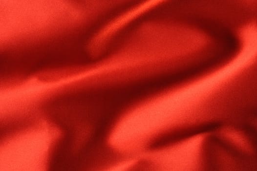 red satin background. A satiny fabric with beautiful light-shadow waves