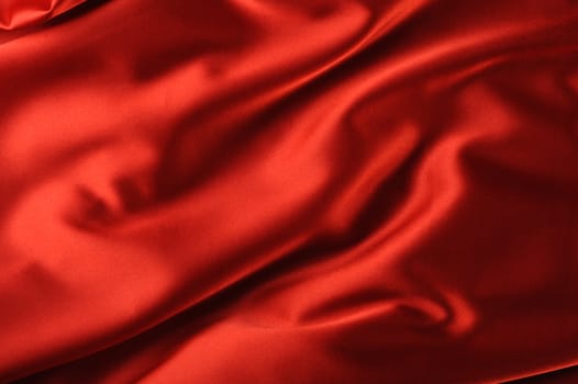 red satin background. A satiny fabric with beautiful light-shadow waves