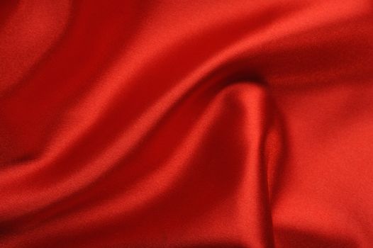 red satin background. A satiny fabric with beautiful light-shadow waves