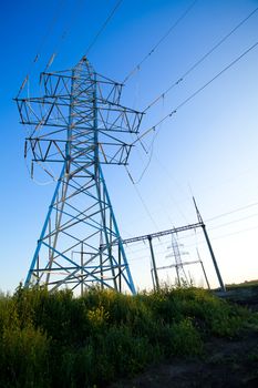 New electric power lines tower in a field over blue morning sky