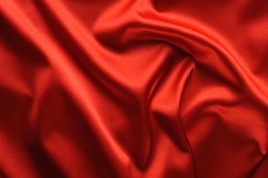 red satin background. A satiny fabric with beautiful light-shadow waves