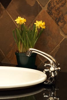 Beautiful sink in a bathroom with yellow daffodil flowers in a pot